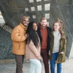 A group of friends smiling and posing outdoors, showcasing winter fashion and diverse togetherness.